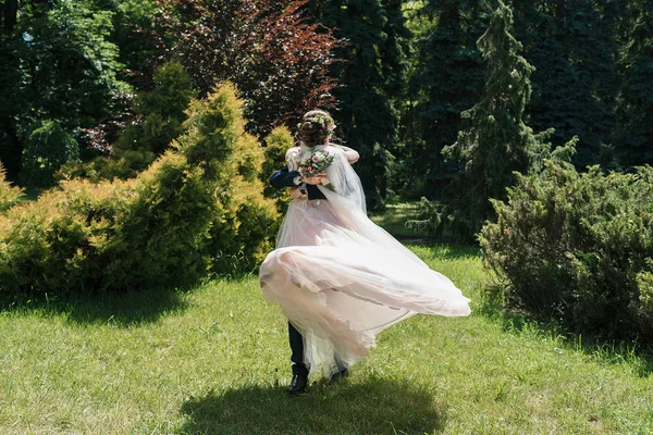 Dans ve having fun güneşli düğün günü genç mutlu evlilik çift. Damat iplik gelin. Elbise rüzgarda geliştirir. Damat holding mutlu duygusal gelin