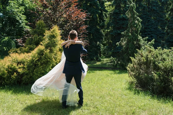 Dans ve having fun güneşli düğün günü genç mutlu evlilik çift. Damat iplik gelin. Elbise rüzgarda geliştirir. Damat holding mutlu duygusal gelin