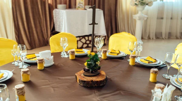 婚礼花安排的黄玫瑰 绿叶和柠檬桩下的表号卡在婚礼餐桌上的模糊 婚宴嘉宾桌位数 — 图库照片