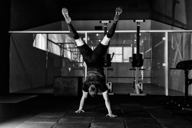 Atlet spor salonunda baş aşağı duran ellerinin üstünde yürümek. Egzersiz yaşam tarzı kavramı. Tam vücut uzunluğu portre