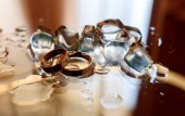 Zlaté snubní prsteny s kostkami ledu na skleněný stůl s kopií prostor