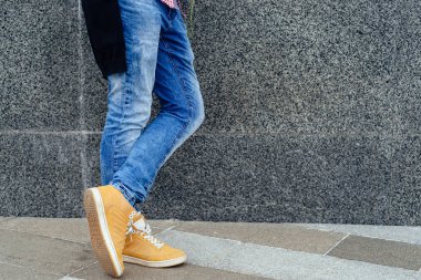 Kot pantolon ve modaya uygun ayakkabı, boş alan adamın ayakları. Sokak dokulu, beton şehir üzerinde duran turuncu ayakkabılı adam. Yakın çekim görünümü adamın deri ayakkabı