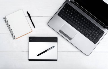 Üstten görünüm açık boş dizüstü bilgisayar, boş günlüğü ve grafik tablet, boş alan beyaz ahşap tablo
