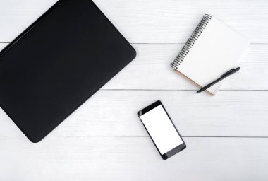 Üstten görünüm dizüstü bilgisayar, cep telefonu ve kalem, boş alan ile boş günlüğü ile beyaz tahta masada. Cep telefonu ile beyaz perde, kopya alanı 