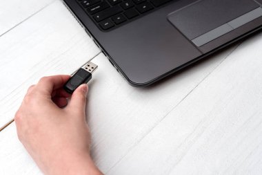 El Beyaz arka plan üzerinde dizüstü bilgisayar USB flash sürücü ekleme. Kadın el dizüstü evde pendrive takmayı kapatın. Dizüstü bilgisayar için flash sürücüden veri kopyalama