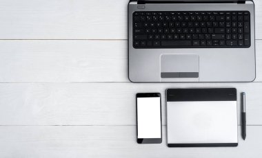 Üstten görünüm açık dizüstü bilgisayar, cep telefonu ve grafik tablet kalem, boş alan ile beyaz tahta masada. Cep telefonu ile beyaz perde, kopya alanı 