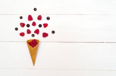 Üstten görünüm tatlı taze organik ahududu ve böğürtlen gözleme koni, boş alan. Koni boş yer beyaz ahşap zemin üzerine taze çilek. Yaz ve sağlıklı gıda kavramı düz