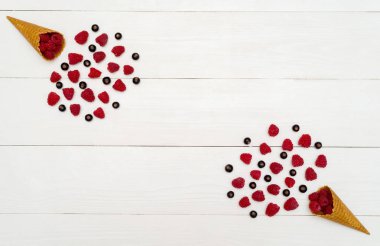 Üstten görünüm tatlı taze organik ahududu ve böğürtlen gözleme koniler, boş alan içinde. Koniler boş yer beyaz ahşap zemin üzerine taze meyveleri. Yaz ve sağlıklı gıda kavramı düz