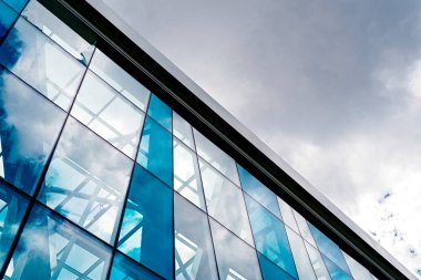 Alt görünümü modern cam mavi iş merkezi mimari, boş alan. Güneş ışığı yansıması cam Özet binasında. Gökyüzü bulutlar arka plan ile. Pencereli köşe ofis binası