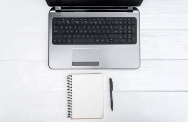 Ahşap beyaz ofis resepsiyon masası açık boş dizüstü bilgisayar ve kalem, boş alan ile boş beyaz günlüğü ile. Üstten görünüm kopya alanı ile. Ahşap arka plan gri laptop