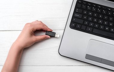 El Beyaz arka plan üzerinde dizüstü bilgisayar USB flash sürücü ekleme. Kadın el dizüstü evde pendrive takmayı kapatın. Dizüstü bilgisayar için flash sürücüden veri kopyalama