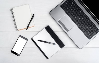 Üstten görünüm ile beyaz tahta masada boş dizüstü bilgisayar, cep telefonu, boş günlüğü ve grafik tablet, boş alan açın. Cep telefonu ile beyaz perde, kopya alanı 