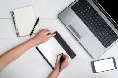 Üstten görünüm açık boş dizüstü bilgisayar, cep telefonu, boş günlüğü ve grafik tablet. Grafiğin ellerimle kızın tablet çizim ve görüntü dizüstü bilgisayarda rötuş boş alan. Cep telefonu ile beyaz perde, kopya alanı 