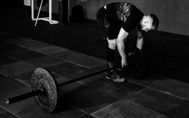 Sakallı adam ağırlık koyarak spor salonunda açık bar. Egzersiz halter ile hazırlanıyor. Vücut geliştirmeci ağırlıkları üzerinde halter koyar.