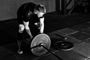 Sakallı adam ağırlık koyarak spor salonunda açık bar. Egzersiz halter ile hazırlanıyor. Vücut geliştirmeci ağırlıkları üzerinde halter koyar.