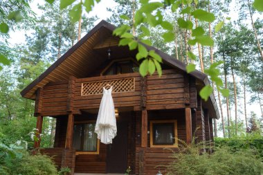 Güzel uzun gelinlik ahşap evin balkonunda açık havada arka plan, boş alan ağaçta asılı