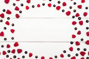 Çerçeve boş yer beyaz ahşap zemin üzerine taze çilek. Üstten görünüm tatlı taze organik ahududu ve böğürtlen. Yaz ve sağlıklı gıda kavramı 