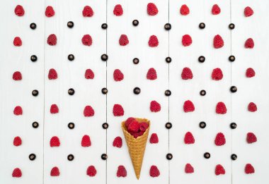 Üstten görünüm bir gözleme koni ile ahududu ve böğürtlen satırlar, boş alan arasında tatlı taze ahududu. Taze çilek koni Beyaz ahşap zemin üzerinde. Yaz ve sağlıklı gıda kavramı düz