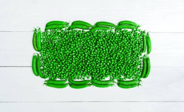 Düz beyaz arka plan, boş alan, gıda arka plan üstten görünüm taze yeşil bezelye ve bakla çerçevenin yatıyordu. Yeşil bezelye üzerinden dikdörtgen