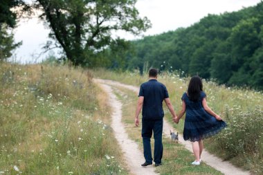 Çift el ele tutuşarak ve patika ile yorkshire terrier köpek açık havada yürüyüş aşık yaz, arka görünümünde forest yakınındaki. Erkek ve kadın yorkie yürüyüş açık havada köpek, boş alan