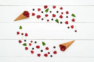 Tatlı taze ahududu, kiraz ve gözleme koni, boş alan siyah kuş üzümü çerçevesinden. Taze çilek koni içinde. Yaz, sağlıklı gıda kavramı, düz yatıyordu, en iyi görünüm. Çilek arka plan. Çilek karışımı