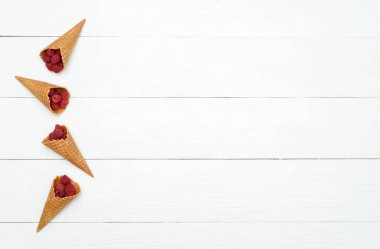 Tatlı taze ahududu gözleme koniler, boş alan içinde en iyi görünümü. Koniler kopya alanı beyaz ahşap zemin üzerine taze meyveleri. Yaz ve sağlıklı gıda kavramı, düz yatıyordu. Çilek arka plan