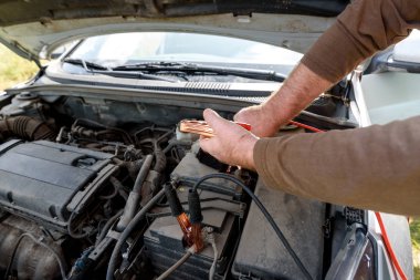 Araba tamircisi ölü pil şarj etmek için pil bağlantı kablosu kullanarak. Araba aküsü ile bakır kelepçeler elektrik yalak bağlantı kablosu ile şarj, uzay kopyalayın. Yolda şarj pil