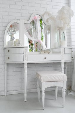 Ayna, tabut, mumlar ve tuğla duvar odadaki beyaz, boş alan yakınındaki bu tüyler beyaz kadının küçük özel odası tablo. Tuvalet masası. Kadının yatak odası iç ayrıntıları. Tablo için makyaj yakınındaki beyaz sandalye