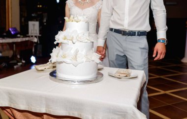 Şık gelin ve damat beyaz çok düzey düğün pastası düğün restoranda taze çiçekler ile yakın duran