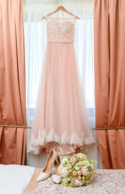 Güzel yemyeşil düğün buket pembe ve beyaz çiçekler ve yatakta gelinin ayakkabılarla gelinlik gelin yatak odasında zemin üzerine 