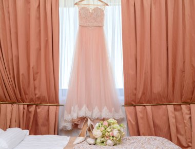 Güzel yemyeşil düğün buket pembe ve beyaz çiçekler ve yatakta gelinin ayakkabılarla gelinlik gelin yatak odasında zemin üzerine 