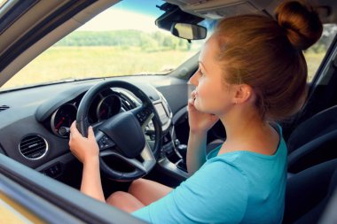 Bir araba ve akıllı telefonda konuşurken güzel genç kadın boş alan. Cep telefonu arabada oturan ve yolda seyir iş kadını