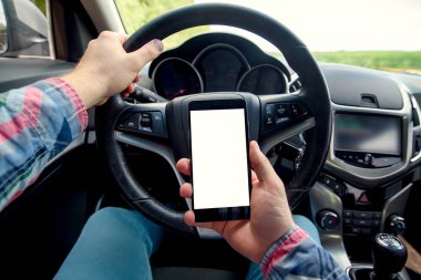 Adam şoför arabaya akıllı telefon istimal Close-up. Arabada oturan ve izole ekranlı mobil akıllı telefon tutarak sürücü. Beyaz boş ekran, metin veya tasarım için kopya alanı ile modern smartphone