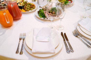 Beyaz masa peçete düğün Resepsiyon, kopya alanı için metin üzerinde boş Konuk kart ile akşam yemeği yer ayarı. Yemekler, gözlük ve çatal bıçak takımı ile sofra. Düğün Ziyafet, yer kartı