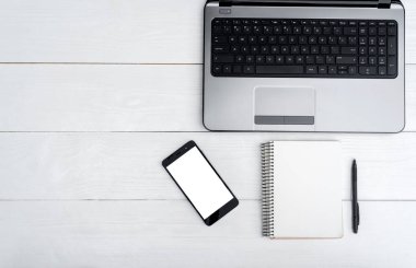 Üstten görünüm açık boş dizüstü bilgisayar, cep telefonu ve kalem, boş alan ile boş günlüğü ile beyaz tahta masada. Cep telefonu ile beyaz perde, kopya alanı 