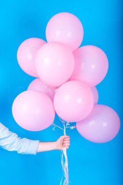 Uçan balon adam elinde beyaz arka plan üzerinde izole mavi hava. Tutan pek çok pembe hava balonları, boş alan mavi tişörtlü adam. Yaz, tatil, kutlama, Doğum günün kutlu ve yaşam tarzı kavramı