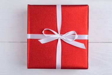 Kırmızı hediye kutusu ahşap arka plan üzerinde beyaz kurdele ile. Tatil tebrik kartı. Anneler günü, Doğum günü, kadınlar günü, annemin günü, Sevgililer günü, yılbaşı, düğün, yıldönümü, 8 Mart. Üstten görünüm, düz yatıyordu