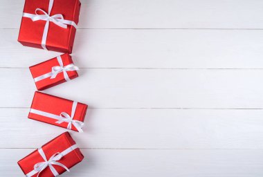 Beyaz ahşap arka plan, kopya alanı üzerinde beyaz kurdele ile kırmızı hediye kutuları. Tatil tebrik kartı. Anneler günü, Doğum günü, kadınlar günü, annemin günü, Sevgililer günü, yılbaşı, düğün. Üstten görünüm, düz yatıyordu