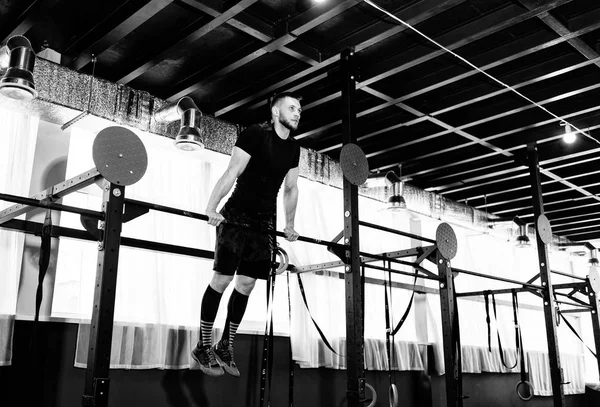 Young man exercising on horizontal bar in the gym. Male adult working out triceps and biceps on horizontal bar