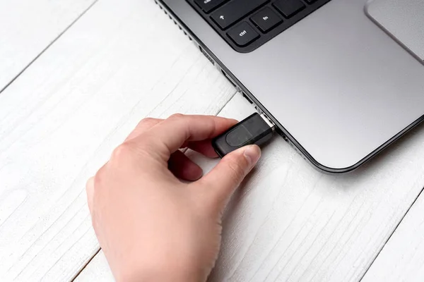 El Beyaz arka plan üzerinde dizüstü bilgisayar USB flash sürücü ekleme. Kadın el dizüstü evde pendrive takmayı kapatın. Dizüstü bilgisayar için flash sürücüden veri kopyalama