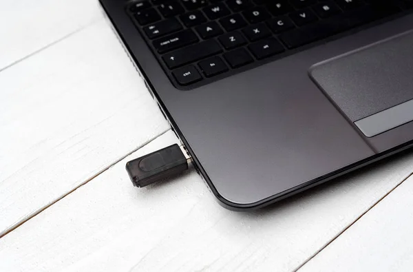 Gray open laptop computer with flash drive in the connector on white background, closeup. Laptop and flash pen drive arranged on table, detail USB connector