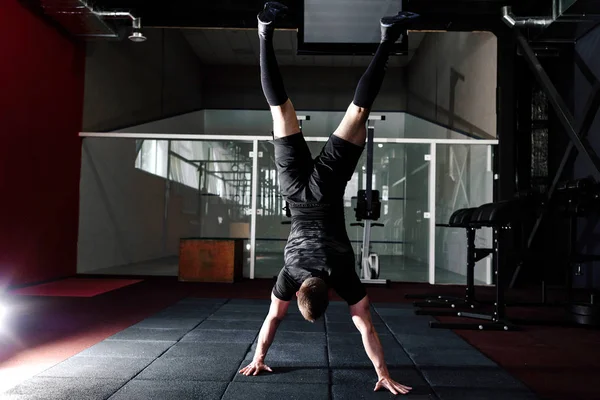 运动员双手倒挂地站在健身房里 男人在手上做俯卧撑 锻炼生活方式的概念 全身长幅肖像 — 图库照片
