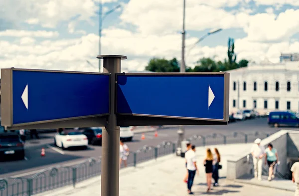 Blank blue street signs with city and people in blur on background, free space for text. Blank blue traffic road signs in bright sky with clouds, free space for text. Blank street sign on cloudy sky background, copy space