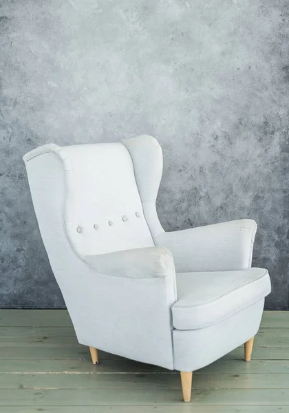 One soft gray velvet armchair near gray wall