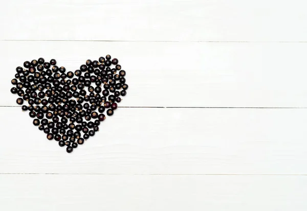 Top view of heart from sweet fresh organic blackberries, free space. Fresh berries in heart on white wooden background with blank space. Summer and healthy food concept flat lay