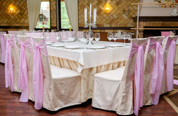 Chairs with beige and pink cloth and table for guests served for banquet. Dinner table for wedding banquet. Table setting