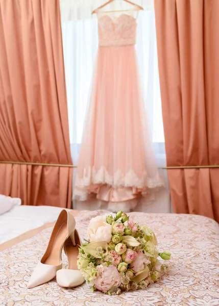 ピンクと白のバラとベッドの上の室内の背景にウェディング ドレス花嫁靴の美しいウェディング ブーケ 結婚式の朝の支度 空き領域です 結婚式の花嫁のアクセサリー — ストック写真