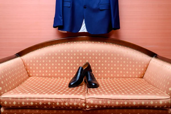 Черные Кожаные Туфли Стоят Диване Голубым Костюмом Висящим Стене Одежда — стоковое фото