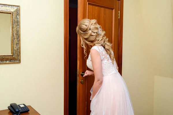 Обаятельная Невеста Свадебном Платье Красивой Прической Стоит Двери Комнате Смотрит — стоковое фото