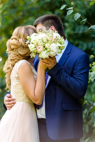 快乐的新娘和新郎与新娘花束亲吻在公园在夏季婚礼当天 亲吻新婚夫妇在爱 新婚夫妇 新娘和新郎的自然 — 图库照片